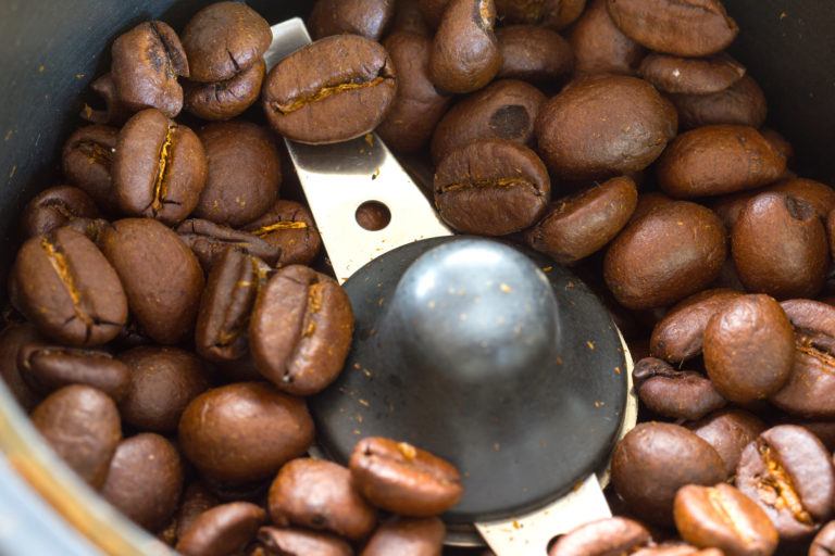 A closeup of coffee beans in a coffee grinder.