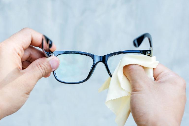 A person cleaning eyeglasses.