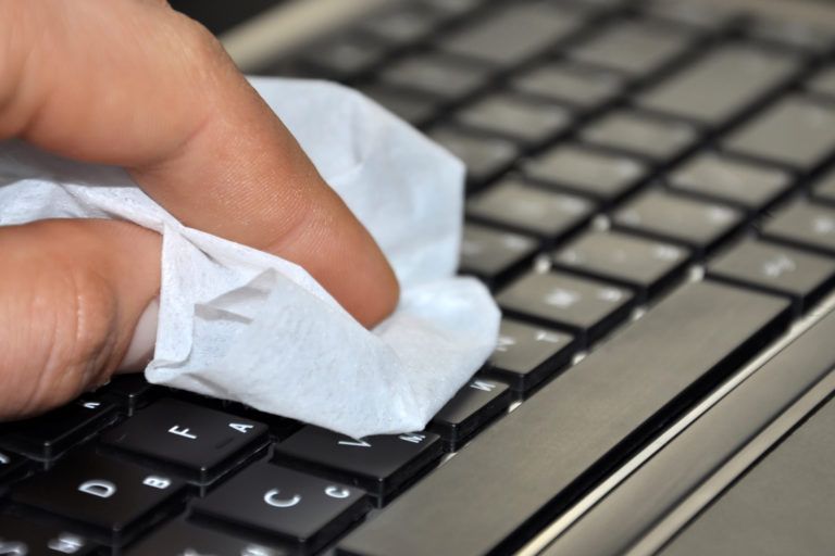 A person cleaning a laptop keyboard.