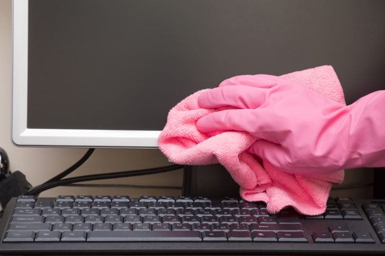 A LCD monitor being wiped down by a person wearing gloves.