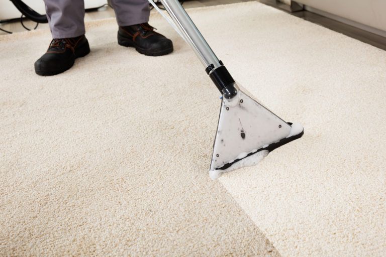 A person shampooing white carpet.