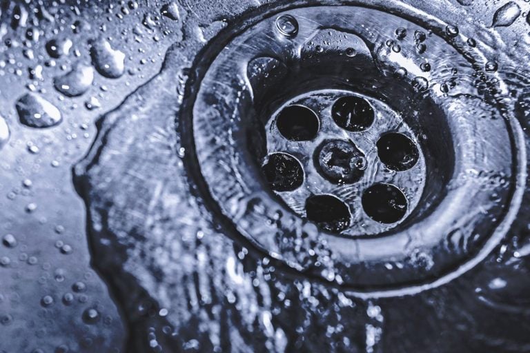 A sink drain with water flowing down it.