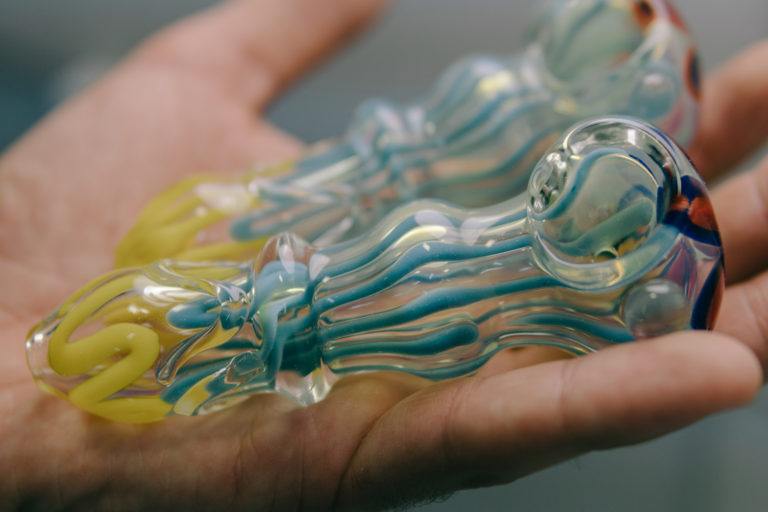 A hand holds two clean glass pipes.
