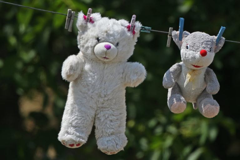 Two stuffed bears hanging on a clothes line to dry.