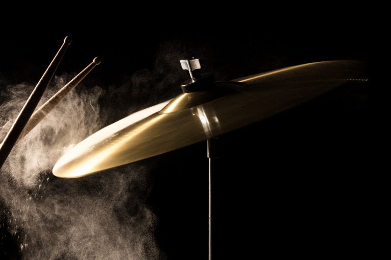 Cymbals being struck by drum sticks and dust flying off them.