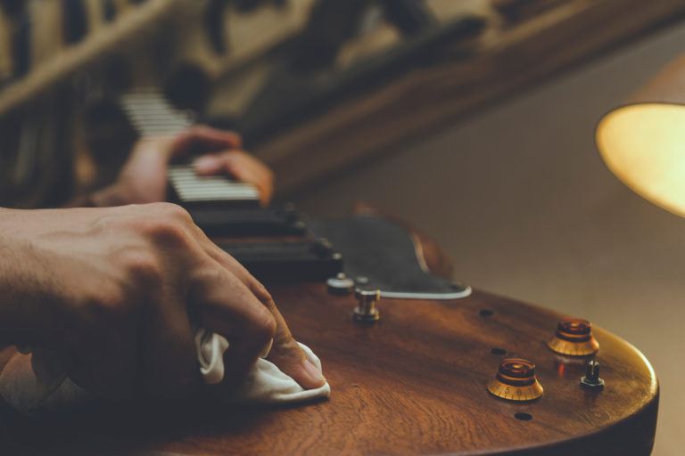 A person wiping down a wooden guitar.