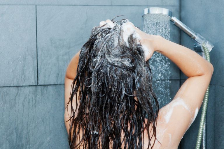 A woman washing her hair in the shower.