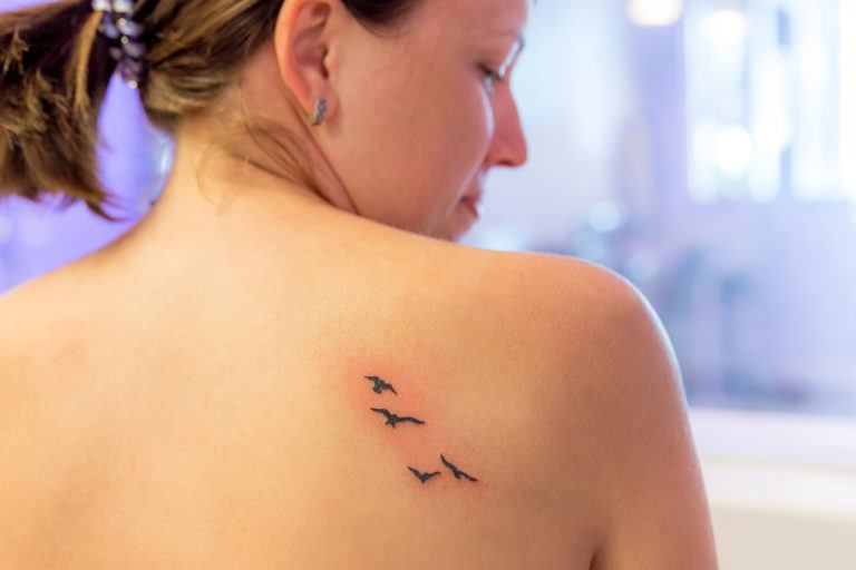 A new tattoo of four birds flying on a woman's back.