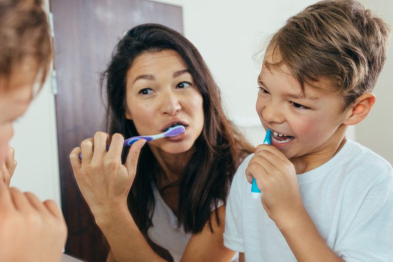 A mother and son brushing their teeth.