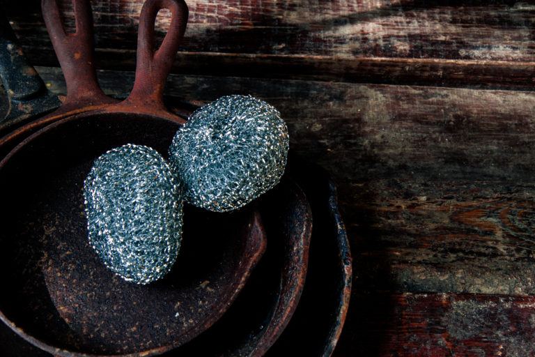 Rusty cast iron skillets with steel wool sitting on them.