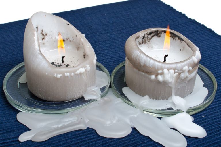 Two white candles have melted onto a fabric table runner.