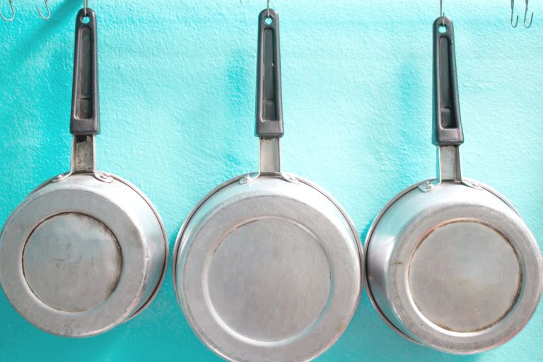 Three aluminum pots hang side by side.