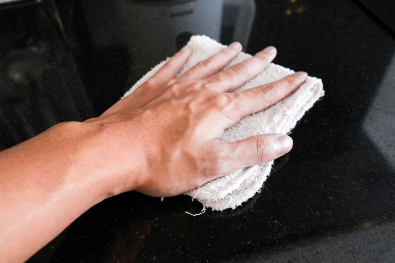 A hand wiping down a marble countertop.