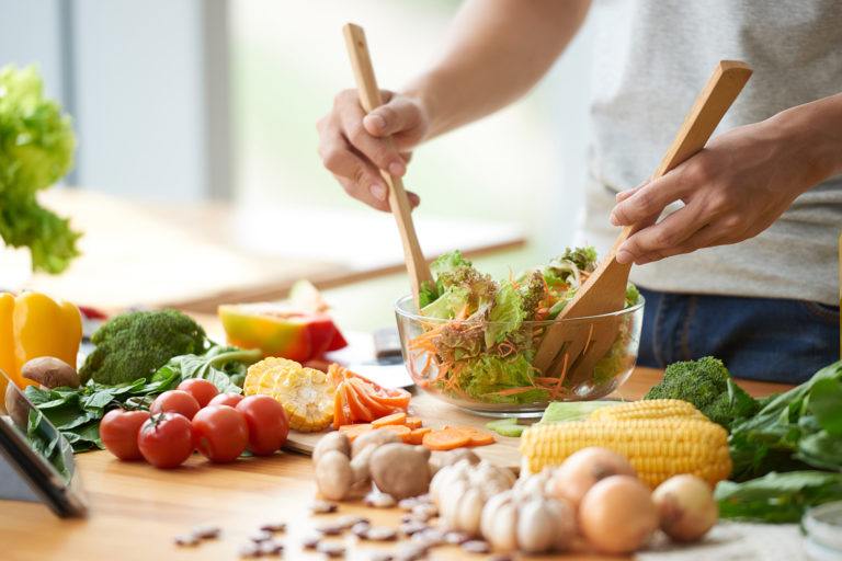 A person preparing a veggie salad.